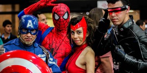 Four people pose in Marvel superhero costumes