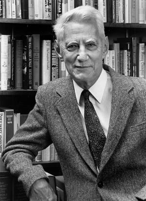 Photograph of Claude Shannon in front of books.
