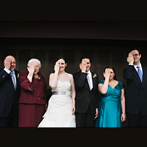 A photo of Jerry Grochow and Louise Grochow at their child's wedding in a group photo with people holding up their hand over one eye to show their MIT Brass rat