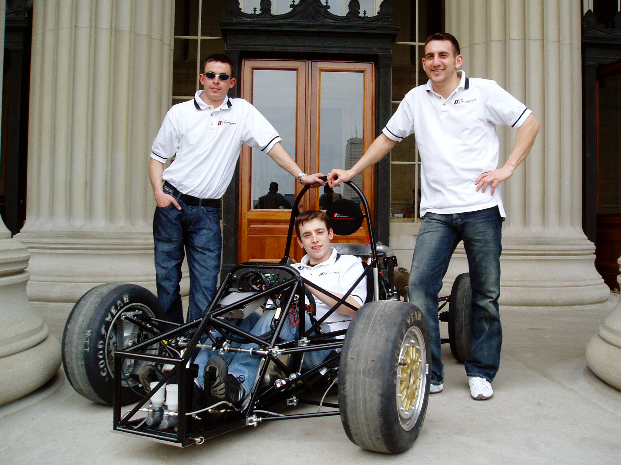 Jim Cuseo SM '05, Richard James ’04, SM ’06, and Joseph Audette ’05 with the MIT Motorsports formula-one style racecar outside the doors of Building 10