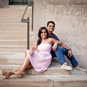 A photo of Payal Agrawal Divakaran and Sanjay Divakaran sitting on the steps of 77 Mass Ave. on MIT's campus