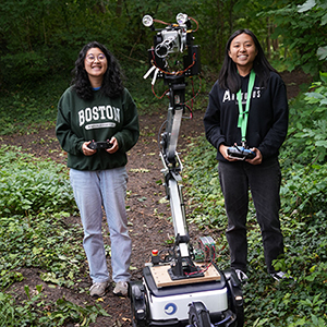 Audrey Chen and Jessica Lam standing in the forest with a robot between them