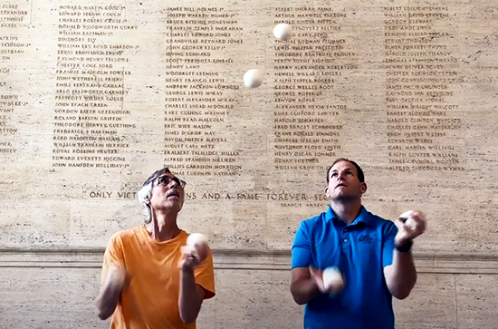 A photo of Arthur Lewbel (left) and David Rush (right) standing in front of a wall with writing on it juggling white balls