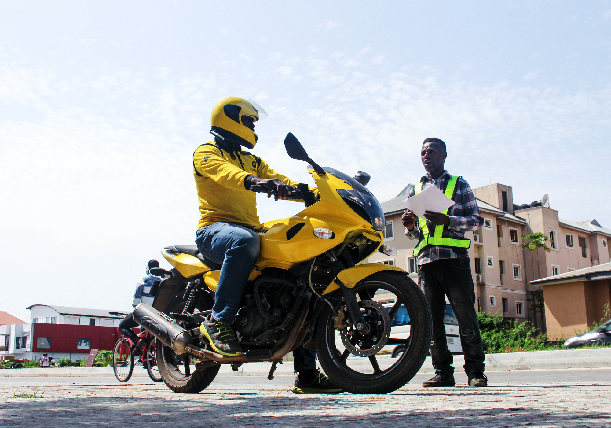 Person on yellow motorcycle talking to a man