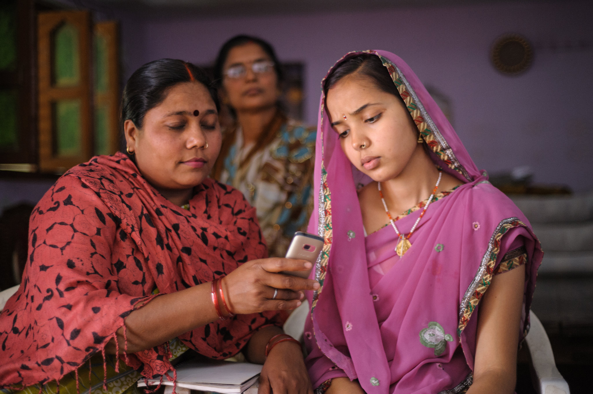 Image provided by the mobile tool Dimagi shows two women looking at a cellular photo.
