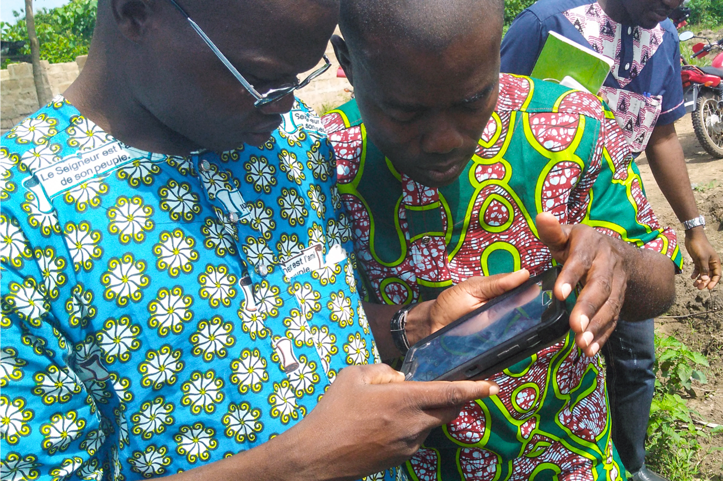 Cocoa farmers in western Africa look at mobile device 