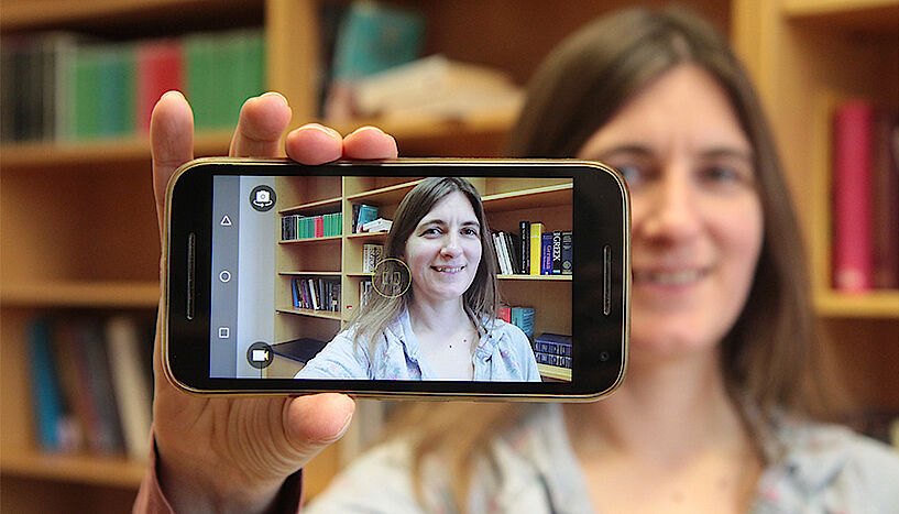 Tara Andrews holding a smartphone, with her face visible through the screen display