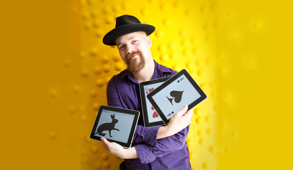 Seth Raphael standing in front of a yellow wall holding tablets with cards and a bunny images on the screen