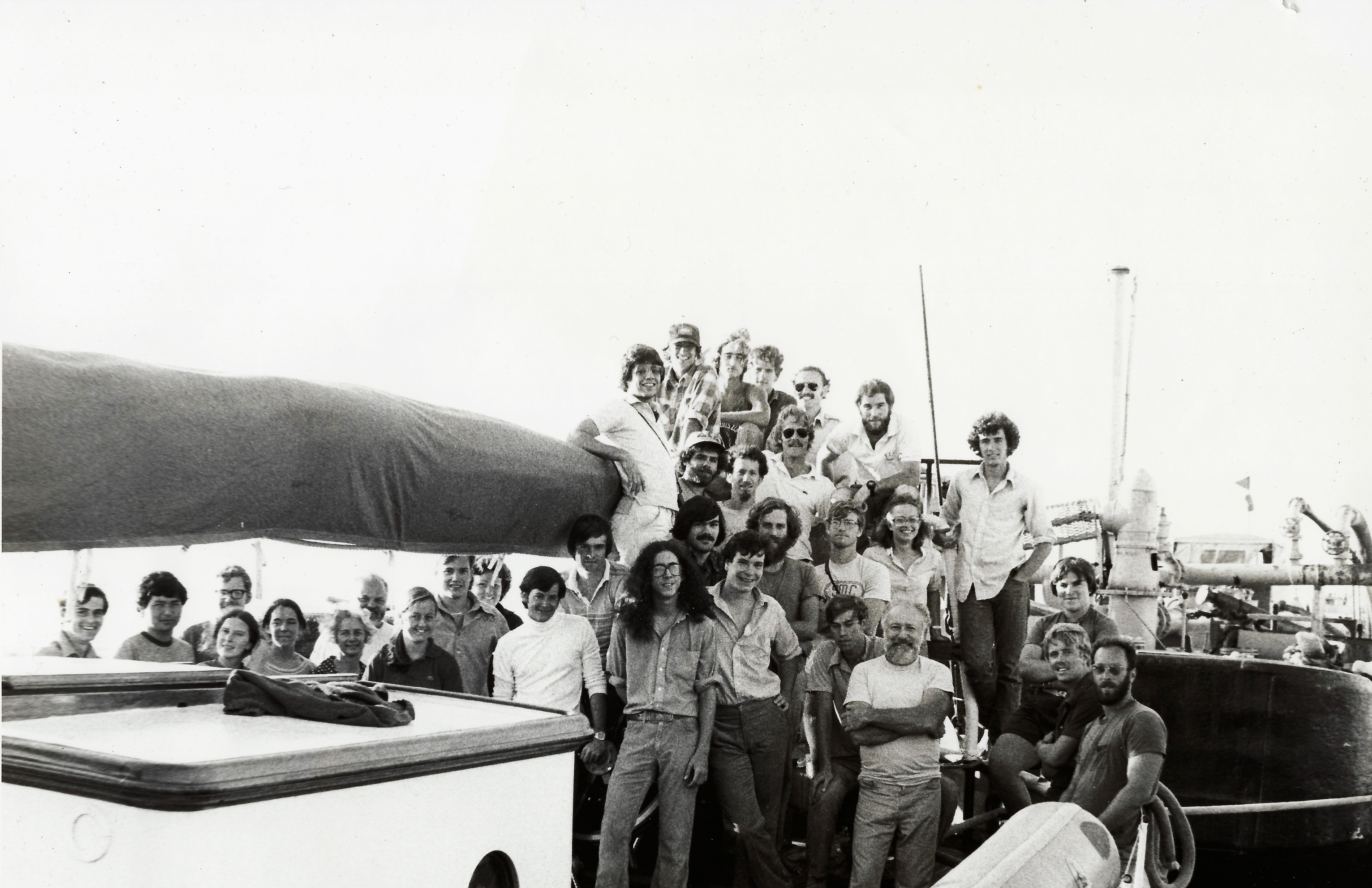 A black and white photo of a group of men and women on a boat 