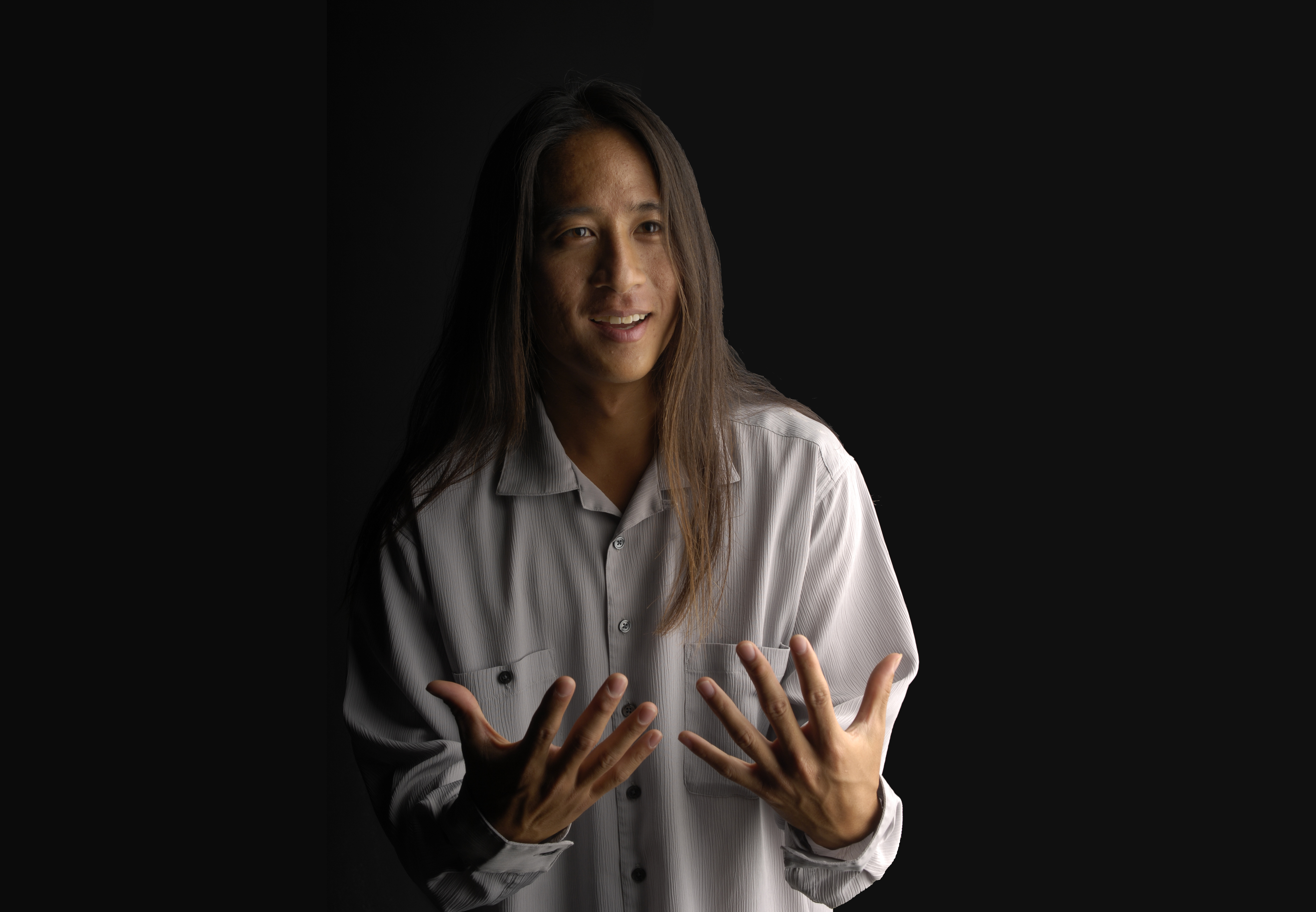Kealoha Wong in front of a black backdrop with his hands out in front of him 