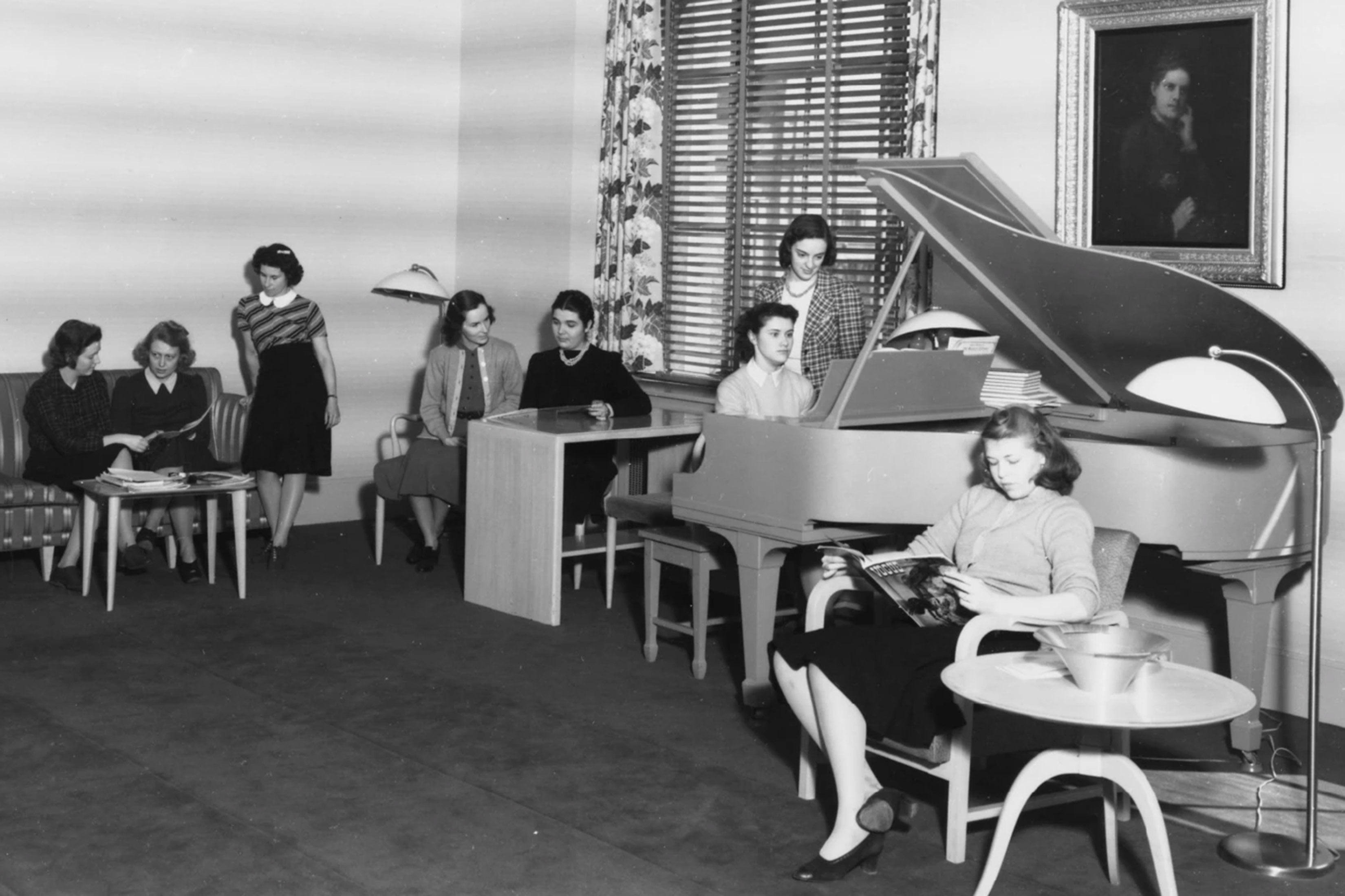 Black and white image from 1940s of women relaxing in a room with a piano