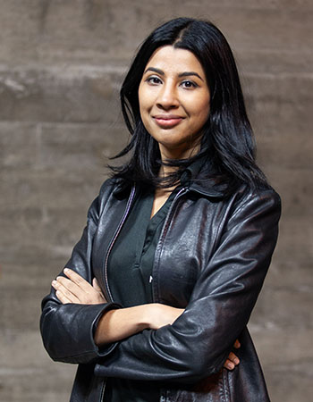 A portrait of Sampriti Bhattacharyya standing with arms folded.
