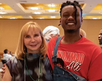 Michele (Gershman) Scavongelli, left, poses with client Elijah Jerome in a room with a few other people visible in the background.