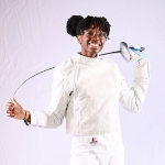 Photo og Kristen Palmer posing in fencing uniform with epee behind her shoulders