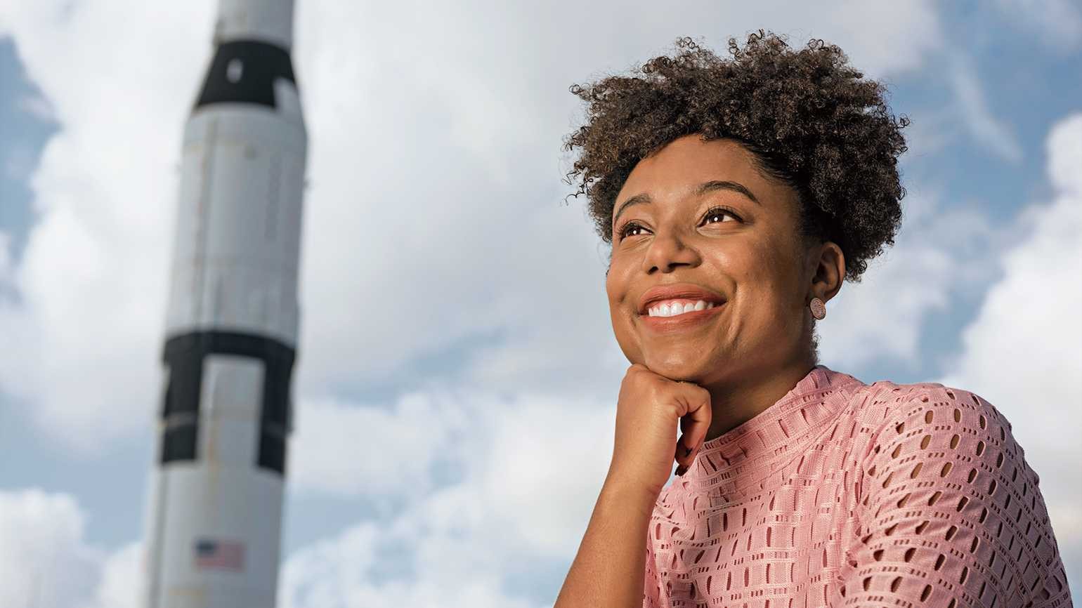 Tiera Fletcher with her chin resting on her fist and a rocket in the background 