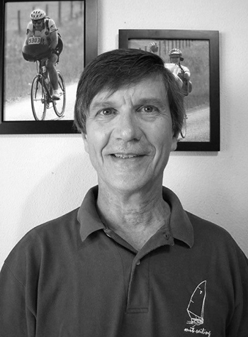 Photo in black and white of Mike Zuteck with two photos on a wall behind him