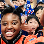 Janelle Wellons at NASA taking a selfie with a group of young kids behind her 