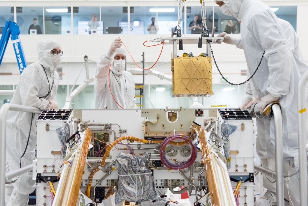 NASA technicians in a clean room install the MOXIE device in the Mars Rover
