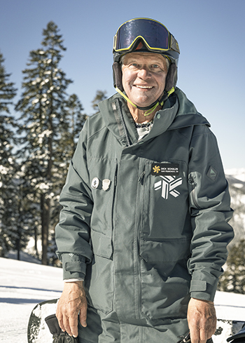 Dick Schulze in snow gear holding a snowboard