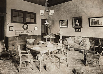 View of 1884 Cheney room features a table, chairs, a couch, and wall hangings.