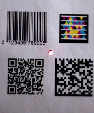 The tiny Bokode device, center, contains far more information than conventional barcodes.