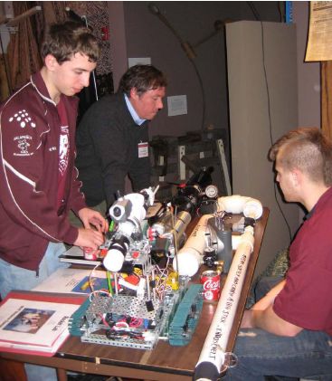 Gloucester High School students CJ Mustone (right) and Brandon Henry (left) describe their engineering projects to Eric Mears ‘80. Photo: DUE