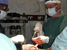 Drs. Jes Bates (right) and Kevin Lakati (orthopedic trauma fellow originally from Kenya who is training with Bates). Bates performs surgery on the first patient to receive Orthopaedic Link equipment in Africa. As there are no surgical drills available, Dr Bates must improvise: this is a drill purchased from a hardware store and covered with a sterile bag.