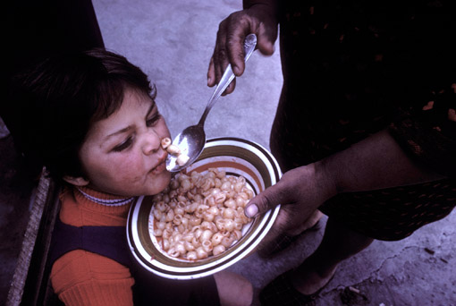 A boy being fed pasta in Naples, Italy (© Owen Franken).