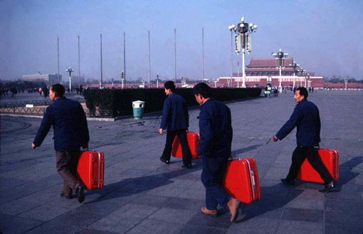 Men walking through Tienanmen Square, having all just bought the same suitcase in a "same suitcase" shop, Beijing, 1983 (© Owen Franken).