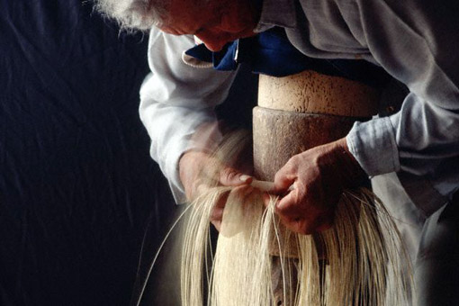 Raul Alarcon Holguin weaves a Montecristi Fino Panama hat as he bends over a weaving stand, placing his chest on wooden blocks. He is using stripped and dried paja toquillo palm fronds to create a fine weave. Pile, Ecuador, 1995 (© Owen Franken/CORBIS).