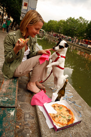 A woman and her dog share a pizza along Canal St. Martin, Paris (© Owen Franken).