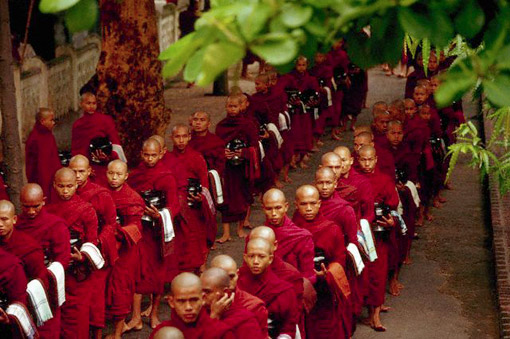 Buddhist monks queue up to receive their lunchtime rice at a monastery in Mandalay, Burma (Myanmar), September 1987. (© Owen Franken).