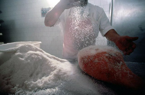 Worker salting a ham in Langhirano, Italy (© Owen Franken).