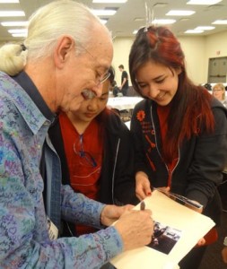 Professor Emeritus Woodie Flowers signs photos for admitted students Sophia Wu and Anna Olson.