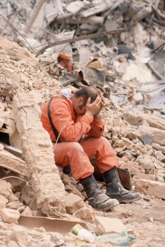 An exhausted rescue worker sits with his head in his hands amid rubble of the 1985 earthquake in Mexico City, Mexico (© Owen Franken/CORBIS).