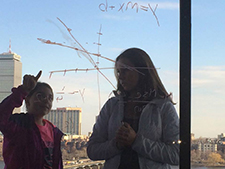 A SHINE student works with her MIT mentor on a math problem in the McCormick Hall Penthouse.