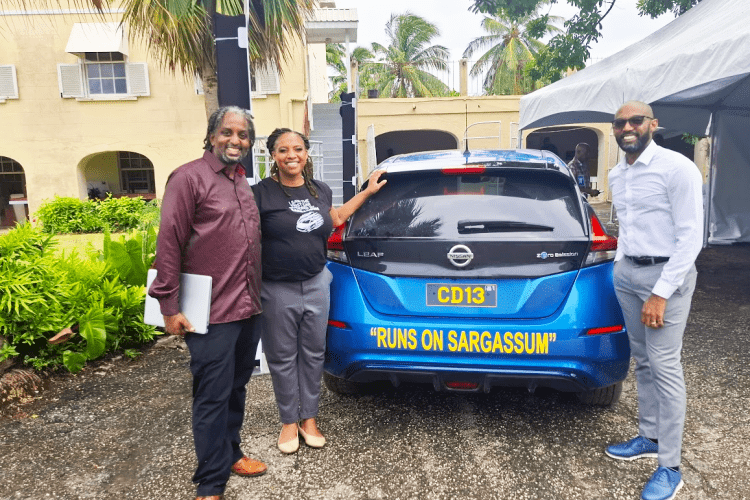 Legena Henry, CEO and cofounder, stands next to a sargassum-powered vehicle during a recent test drive with Nigel Henry, cofounder and managing director (left), and Lorenzo Hodges, technical advisor