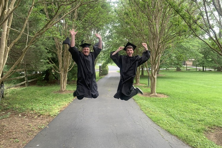 Man and his father in graduation attire jumping