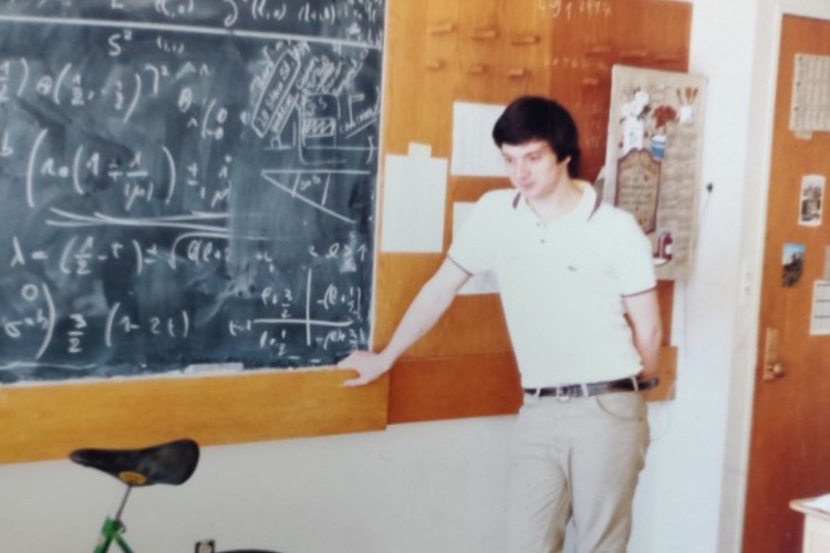 Stefano Forte as an MIT student standing in front of a chalk board with an equation on it