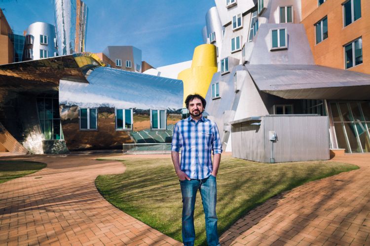 MIT alum Greg Falco standing in a courtyard outside in front of the MIT Stata Center