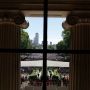 Pillars of Killian court frame a view of the commencement ceremony with the Boston skyline in the background