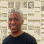 Ken Granderson stands in front of a collage of Black History facts from his website