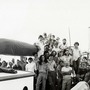 A black and white photo of a group of men and women on a boat 