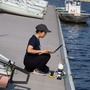 Woman in a hat kneeling on a boat launch with a laptop
