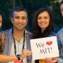 Chest up shot of four people (two women, two men) smiling and holding a sign that says "We [heart] MIT!"