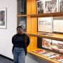 Deborah Tsogbe stands to the left of a large display case in the MIT Rotch Library