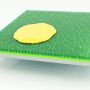 Illustration shows a yellow blob on a square green surface. The green material looks rubbery and appears to have spikes embedded in it.