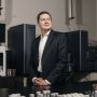 Sean Hunt stands in a room filled with lab equipment.