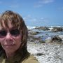 Darleen Ketten is shown in closeup, wearing sunglasses. A beach scene is behind her.