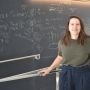 Alex Reiss-Sorokin stands in front of a blackboard full of equations.